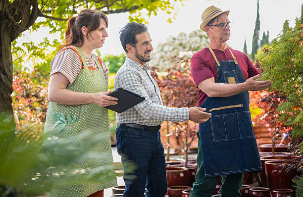 istock Man in Blue Apron Guiding Customers through Garden Center 2249988111