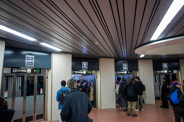 Commuters waiting in line to use multiple elevators at an underground metro station during rush hour.