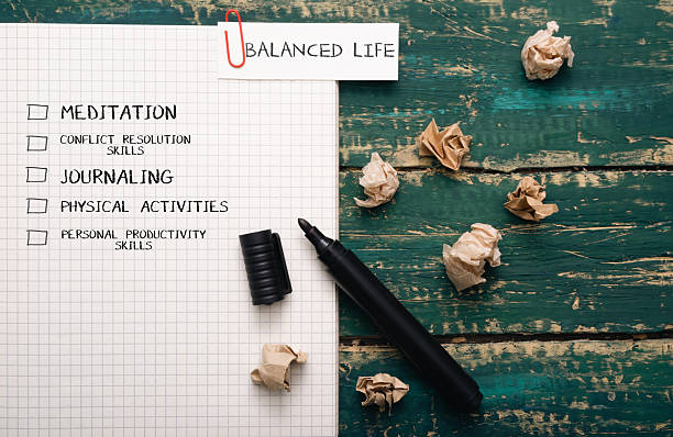 istock Notebook with checklist for balanced life, featuring meditation, journaling, physical activities, and productivity skills, surrounded by crumpled paper and a black pen on a wooden table 2249989570