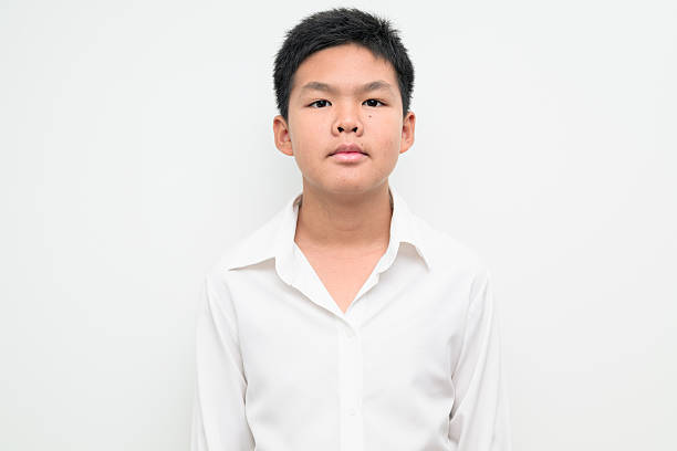 Studio portrait of an Asian teenage boy student standing against a plain white background wearing button down shirt. Simple look suitable for youth, education, family, and lifestyle themes.