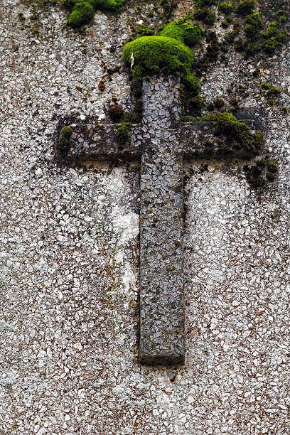 istock Moss-covered Stone Cross on a Weathered Wall 2249994545