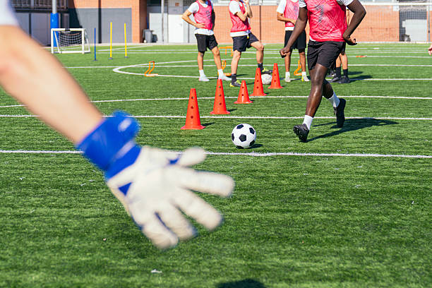 In the image, a person is seen blurry while executing a kick on a soccer field as they attempt to strike a soccer ball