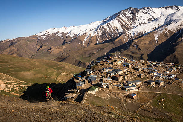 Mountain biker rides down mountain slope to village