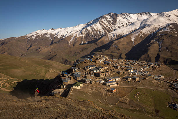 Mountain biker rides down mountain slope to village