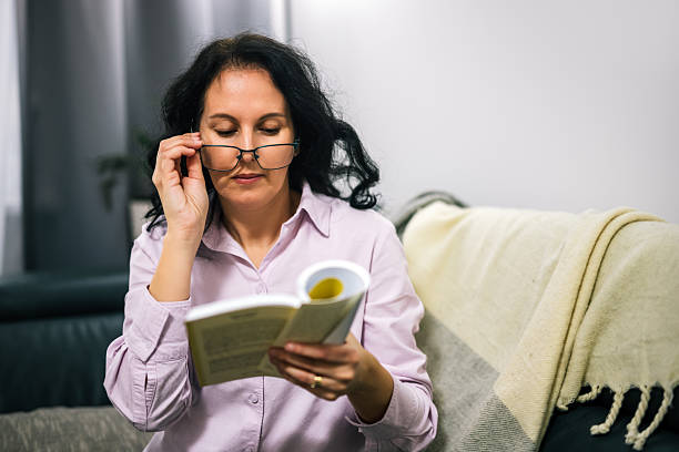 istock Middle-aged woman reading a book with reading glasses 2250003966