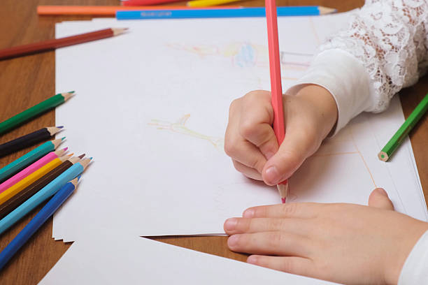istock Young kid creating simple drawing with pink pencil on large sheet 2250005649