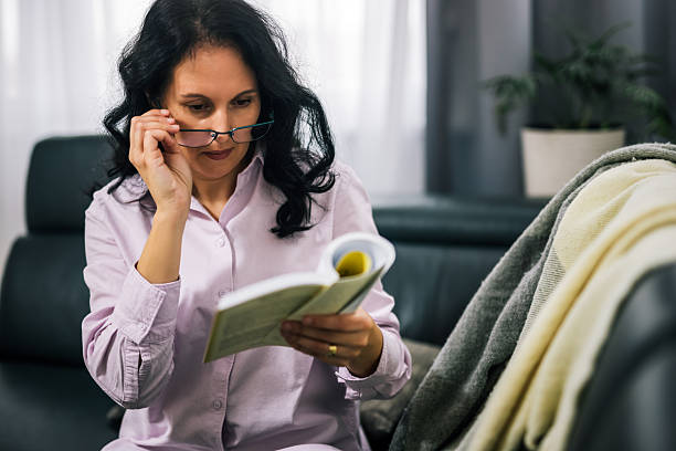 istock Woman wearing glasses reading on sofa 2250007744