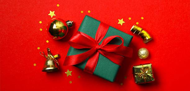 istock Festive holiday scene with wrapped present and decorations on a bright red background conveying Christmas cheer and celebration. Top view, space for text 2250009460