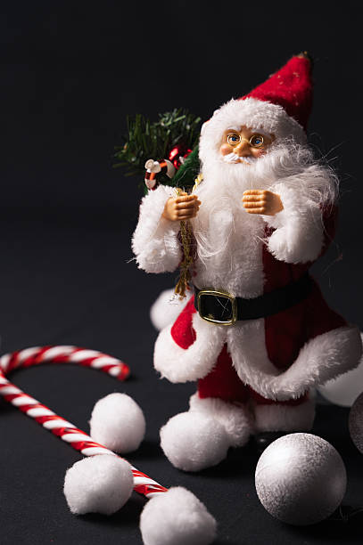 Closeup Santa figurine red suit smiling, handcrafted texture and fine details visible. warm directional light highlights plush beard, velvet fabric and gold