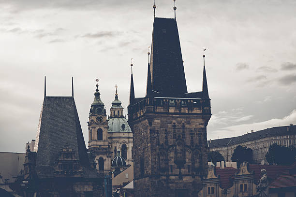 The majestic Old Town bridge tower overlooks charming rooftops of Prague on a cloudy day, showcasing rich history and stunning architecture. Czech Republic