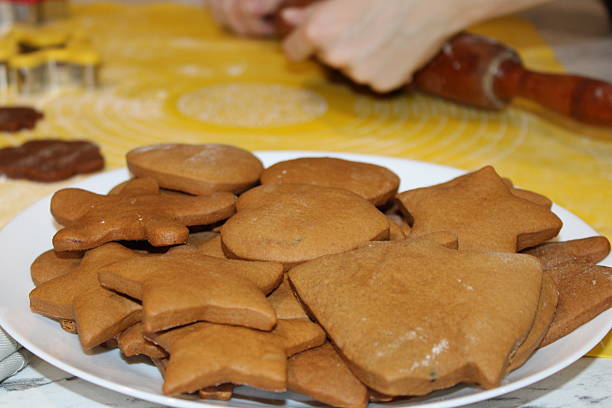 istock Baking gingerbread cookies in the kitchen with rolled dough on a yellow surface and cookie cutters in use 2250015189