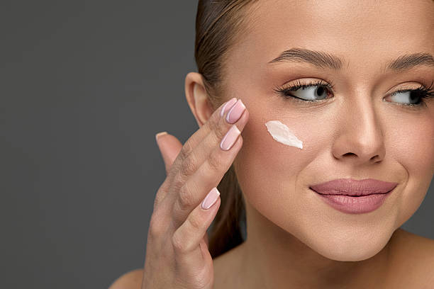 istock Woman applying moisturizing lotion to her face while preparing for a skincare routine in a clean and minimalistic environment 2250016092