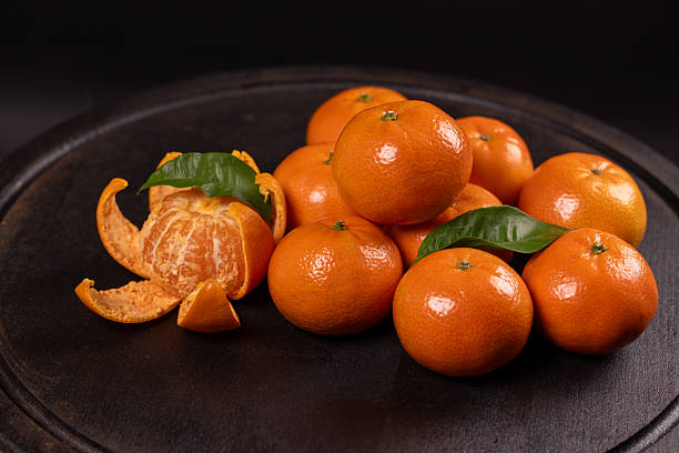 istock Fresh mandarins with peel and green leaf on black background 2250022274