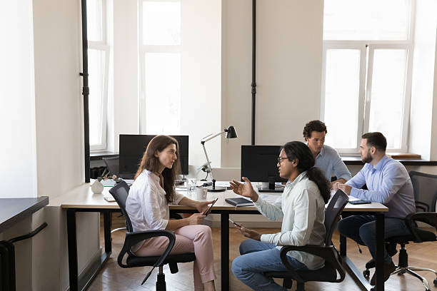 istock Pairs of busy multiethnic office colleagues talking at shared workplace 2250023952