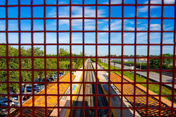 Looking at railroad tracks through a metal grid fence