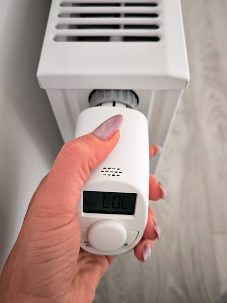 istock A woman's hand adjusts a modern thermostat on a radiator. 2250026320
