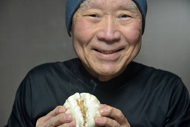 istock A senior smiling as he eats a steaming steamed bun 2250026552