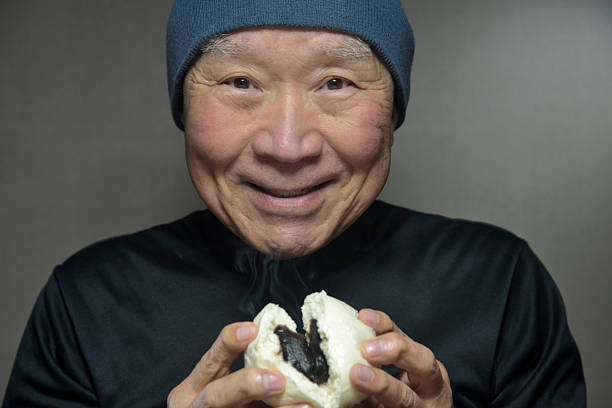 istock A senior smiling as he eats a steaming steamed bun 2250026567