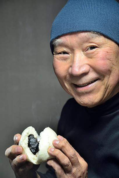 istock A senior smiling as he eats a steaming steamed bun 2250026573
