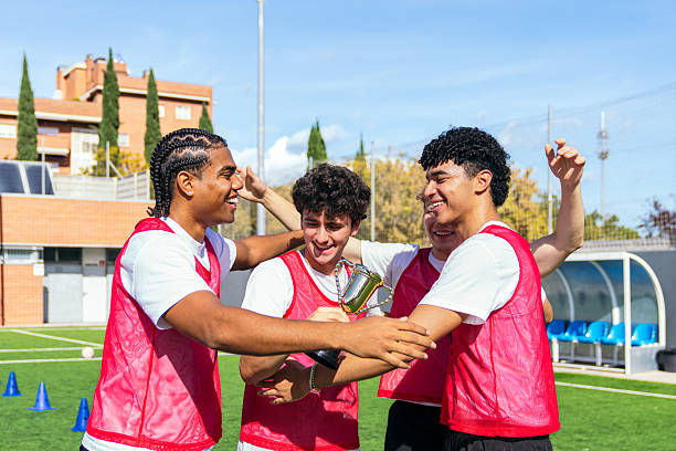 Young male soccer players celebrating their championship victory on the field, holding a trophy and showing joy
