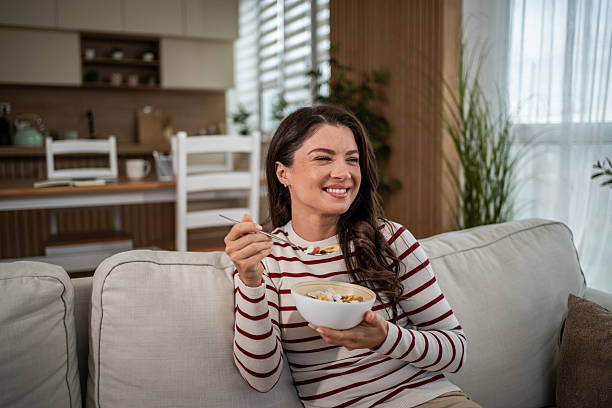 istock Young woman enjoying healthy breakfast cereal on sofa 2250031111
