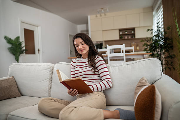 istock Woman relaxing at home reading book on couch 2250031770
