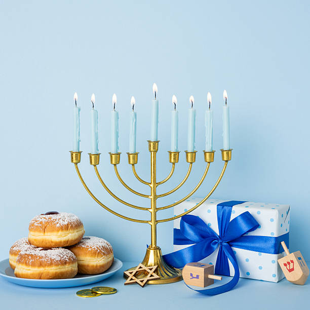 istock A festive Hanukkah scene features a lit menorah, donuts with powdered sugar, and a blue gift box with a ribbon, conveying tradition, warmth, and holiday greetings 2250033649