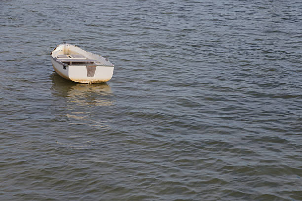 A lone white rowboat drifts on tranquil sea water, reflecting soft light. The scene conveys solitude and peacefulness, ideal for travel, coastal lifestyle, or nature and relaxation themes.