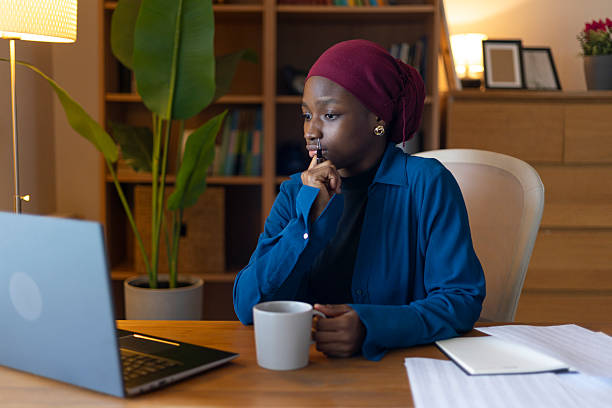 istock African-american muslim woman wearing a hijab working from home, thinking and analyzing data on her laptop during a remote video conference call 2250040010