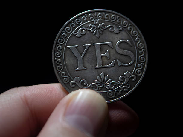 Hand Holding a Coin with 'YES' Engraved on It