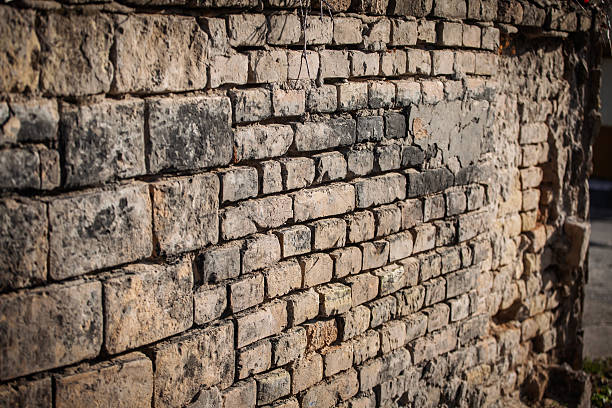 istock Close view of a crumbling brick wall shows weathered masonry with cracks, missing mortar, and textured stone, capturing decay and age in an urban setting, emphasizing surface detail and deterioration. 2250041370