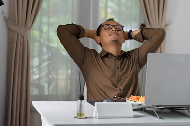 istock Relaxed Indonesian Man Leaning Back with Hands Clasped Behind Head in Home Office 2250045401
