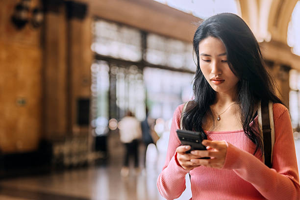 istock Chinese woman using her phone at train station in Spain while waiting for her train 2250046221