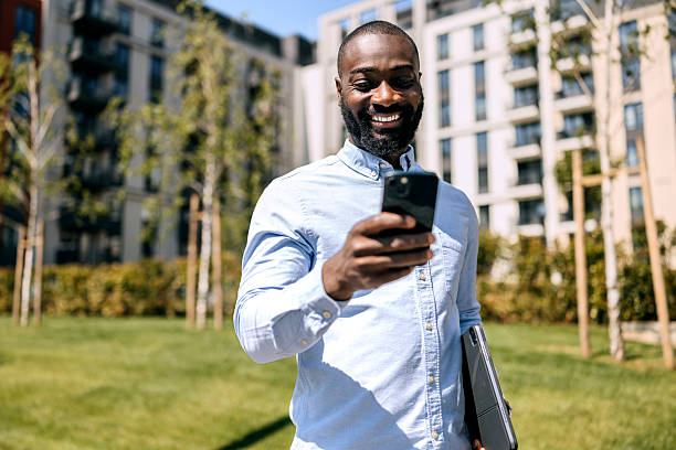 istock Black businessman smiles while using smartphone outdoors in a city area during daytime 2250047665
