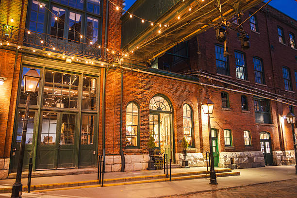 Historic brick architecture illuminated by warm streetlights and string lights in the Distillery District of Toronto at night. High quality photo