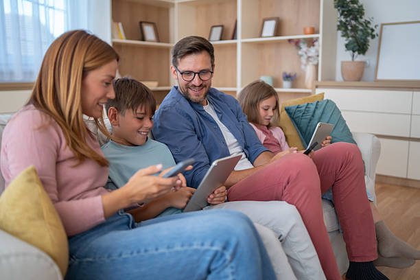 istock Family relaxing on sofa using electronic devices at home 2250058223