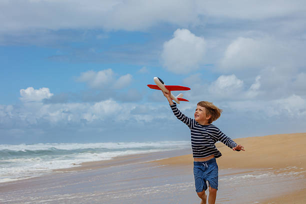istock Laughing child sprints along the beach with his toy red plane 2250058695
