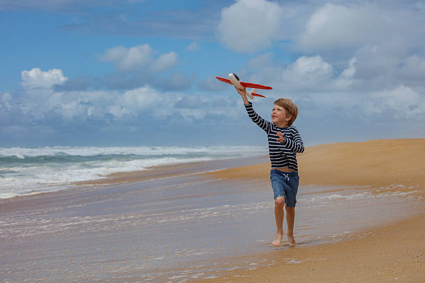 istock Child runs joyfully on a beach hold and fly red toy airplane 2250058708