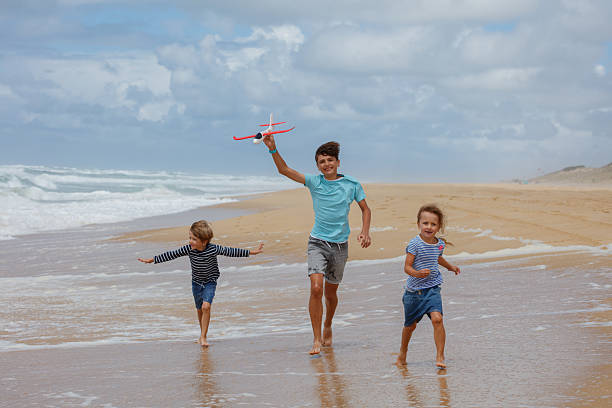 istock Children run on windy sandy shore launching a bright red plane 2250058710