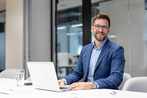 istock Smiling businessman working on laptop in modern office 2250058792