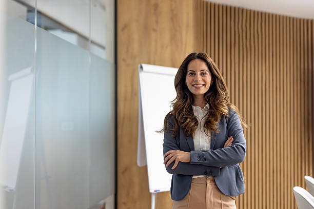 istock Businesswoman smiling with folded arms in modern office 2250058823