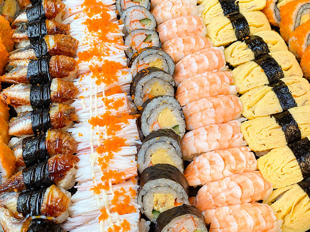 Assorted sushi platter featuring tamago rolls, crab stick rolls, tamago, unagi, ebi, and kani, beautifully arranged on a serving tray for catering events.