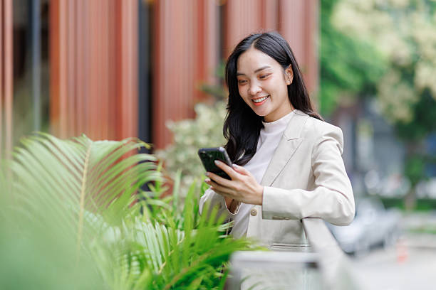 istock Smiling businesswoman using smartphone near office building 2250062274