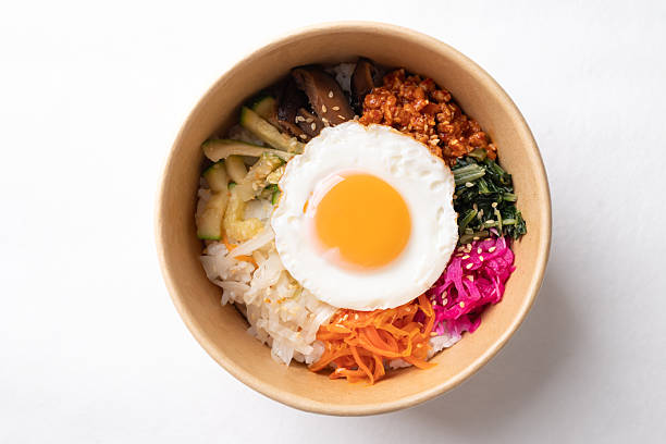 Bibimbap, Korean food, Cooked rice with vegetables, pork and egg in biodegrable bowl on white background