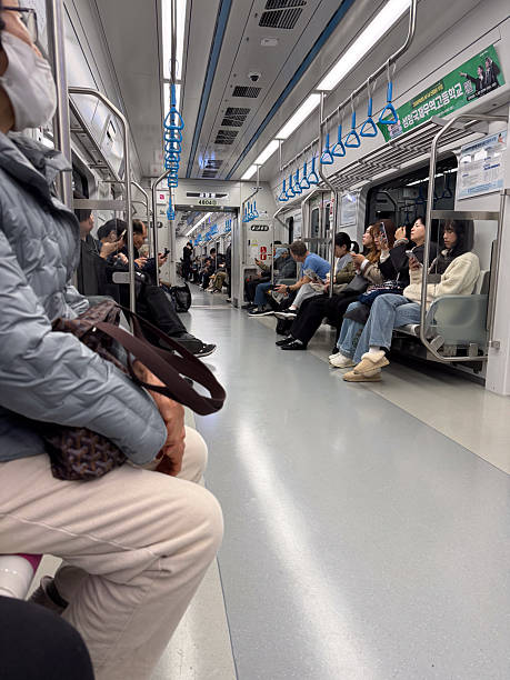 Suwon, South Korea, November 8, 2025. Passengers riding a modern subway train in Seoul, Korea, using mobile phones while commuting in the busy city