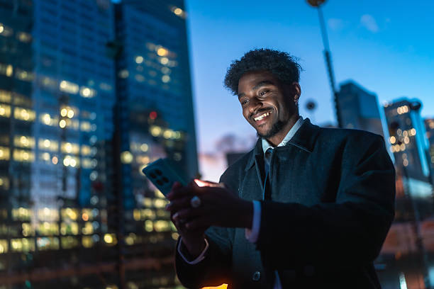 istock Young black man smiling using smartphone in city at night 2250078183