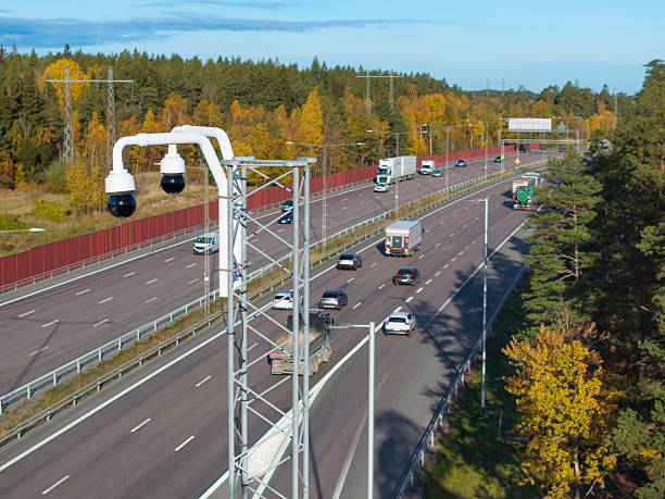 Surveillance cameras above the traffic in a large highway.