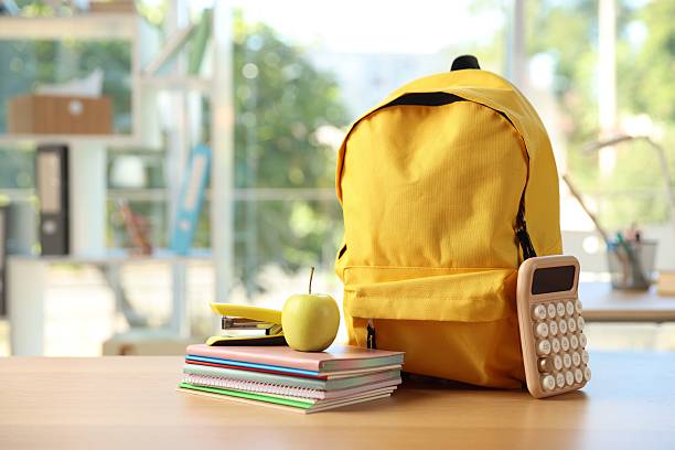 istock Backpack, different stationery and apple on desk in classroom 2250080107