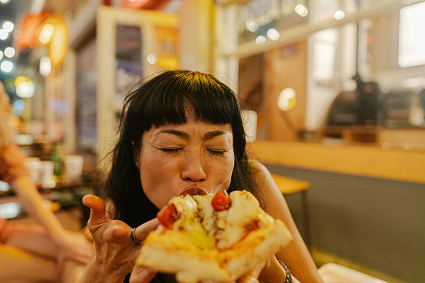 istock An Asian woman eating pizza 2250082341