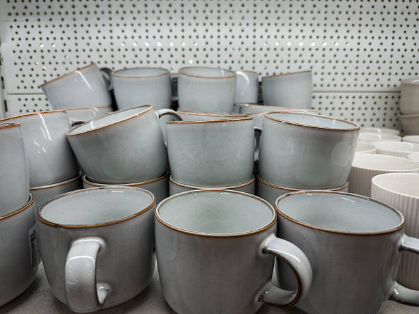 istock A stack of minimalist ceramic mugs displayed on a store shelf. Matte light-gray cups with subtle brown edging create a clean, modern look, representing kitchenware shopping and home essentials. 2250083549